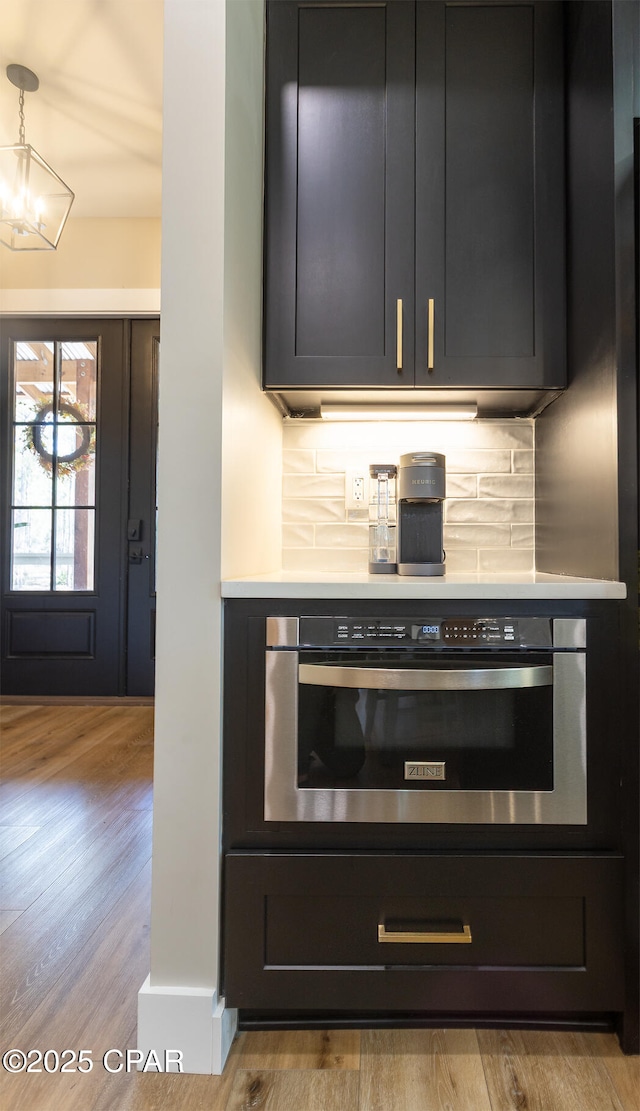 kitchen with light countertops, wood finished floors, backsplash, and oven