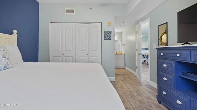 bedroom featuring a closet, visible vents, light wood-type flooring, and baseboards