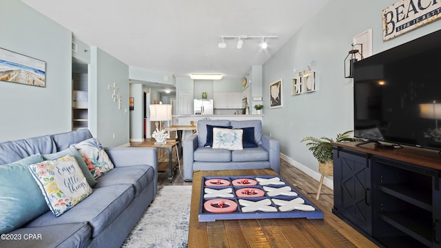 living area featuring track lighting, baseboards, and wood finished floors