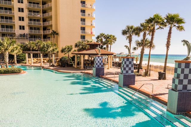 view of swimming pool with a gazebo, a beach view, a patio, and a water view