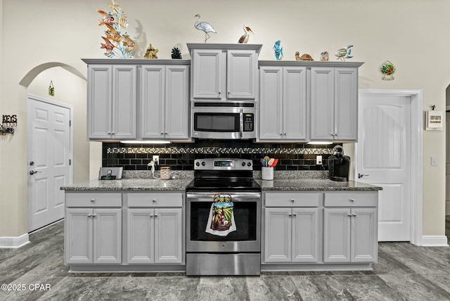 116 Lake Merial Blvd, Panama City, FL 32409 - kitchen with stainless steel appliances, decorative backsplash, light stone countertops, and arched walkways