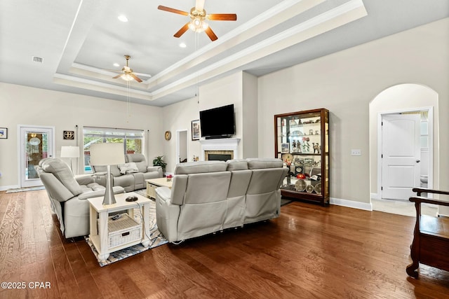 116 Lake Merial Blvd, Panama City, FL 32409 - living area featuring a ceiling fan, a tray ceiling, ornamental molding, dark wood-style floors, and arched walkways