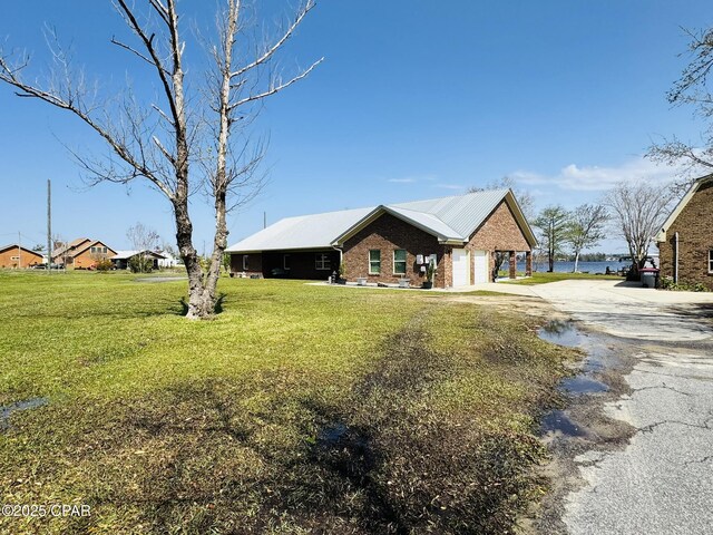 7224 Resota Ln, Panama City, FL 32409 - view of front of home featuring an attached garage, brick siding, driveway, a front yard, and metal roof