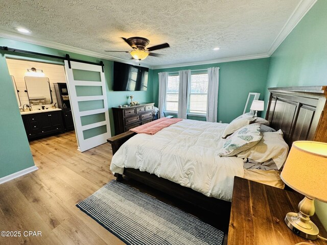 7224 Resota Ln, Panama City, FL 32409 - bedroom featuring a textured ceiling, a barn door, light wood-type flooring, crown molding, and connected bathroom