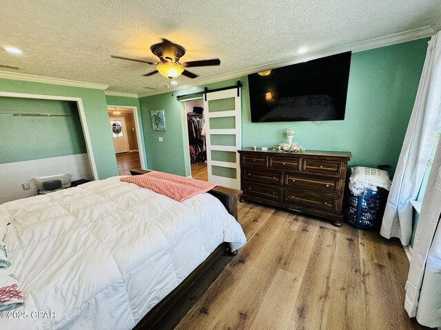 7224 Resota Ln, Panama City, FL 32409 - bedroom with light wood finished floors, crown molding, a textured ceiling, and a barn door