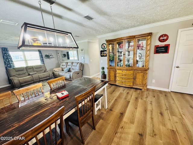 7224 Resota Ln, Panama City, FL 32409 - dining area featuring a textured ceiling, baseboards, visible vents, crown molding, and light wood-type flooring