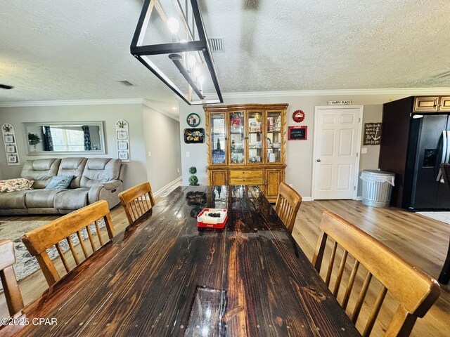 7224 Resota Ln, Panama City, FL 32409 - dining area featuring wood finished floors, a textured ceiling, visible vents, baseboards, and ornamental molding