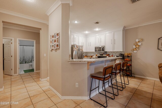107 Summerwood Dr, Panama City Beach, FL 32413 - kitchen with stainless steel appliances, light tile patterned floors, a kitchen breakfast bar, backsplash, and white cabinets
