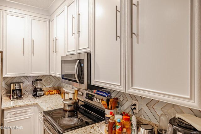 107 Summerwood Dr, Panama City Beach, FL 32413 - kitchen with appliances with stainless steel finishes, tasteful backsplash, white cabinets, and light stone countertops