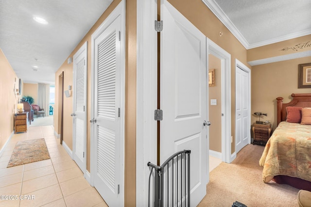 hallway with crown molding, baseboards, light colored carpet, light tile patterned floors, and a textured ceiling