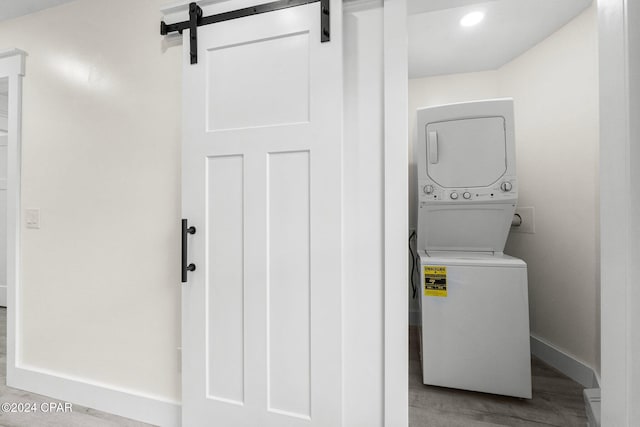 5408 Lagoon Way Unit 5, Panama City, FL 32408 - laundry room featuring wood finished floors, baseboards, laundry area, stacked washer and clothes dryer, and a barn door