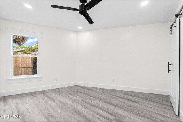 5408 Lagoon Way Unit 5, Panama City, FL 32408 - unfurnished room with a barn door, baseboards, light wood-style flooring, and a ceiling fan