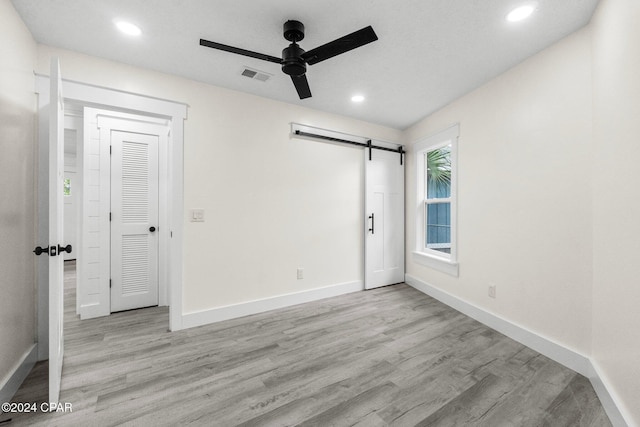 5408 Lagoon Way Unit 5, Panama City, FL 32408 - unfurnished bedroom featuring visible vents, light wood-style flooring, baseboards, and a barn door
