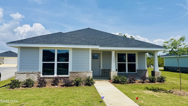 view of front facade featuring a porch, a shingled roof, and a front yard