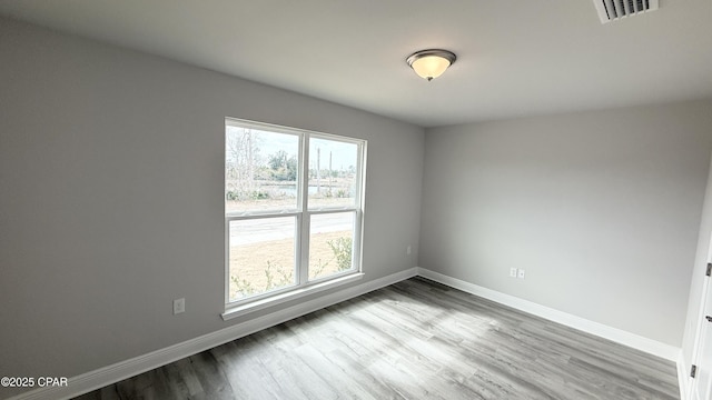 spare room with visible vents, wood finished floors, and baseboards
