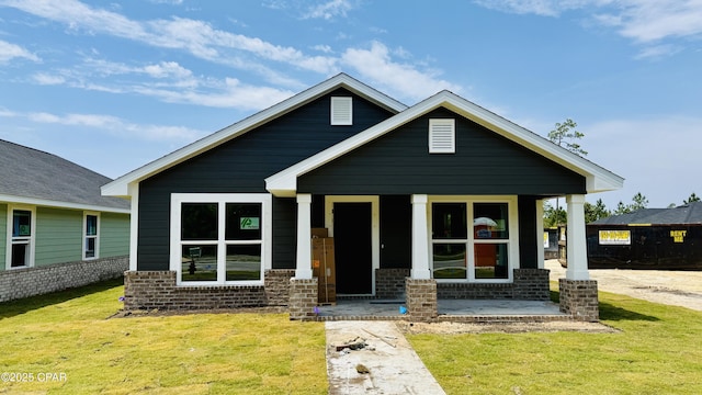 bungalow-style home with covered porch, a front yard, and brick siding