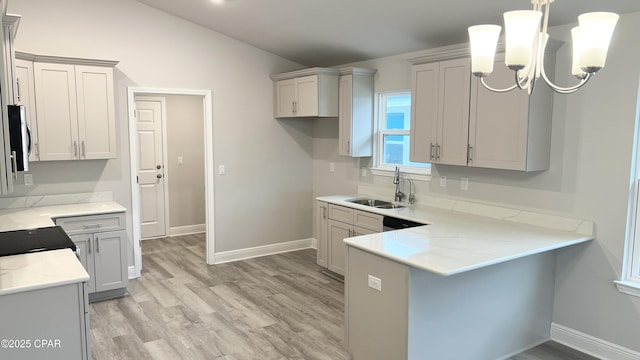 kitchen with light wood-style floors, vaulted ceiling, a sink, baseboards, and a peninsula