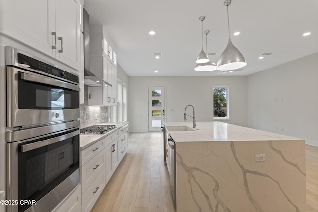 17 Woodland Dr, Santa Rosa Beach, FL 32459 - kitchen with decorative backsplash, light wood finished floors, wall chimney exhaust hood, stainless steel appliances, and a sink