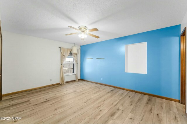 spare room featuring baseboards, a textured ceiling, ceiling fan, and wood finished floors
