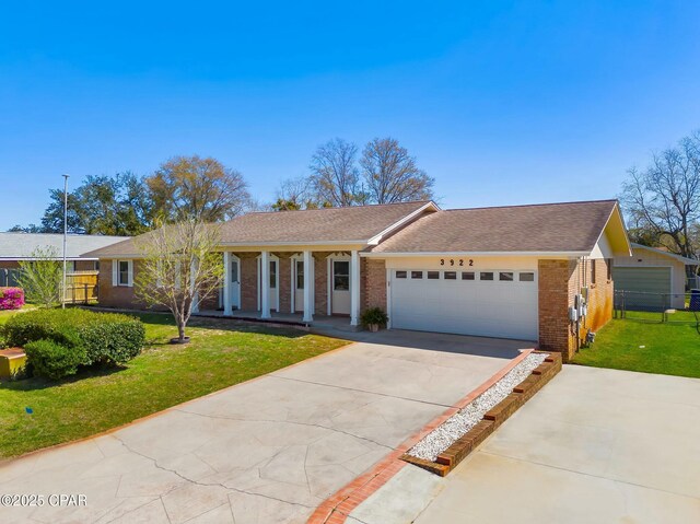 ranch-style house with driveway, fence, an attached garage, brick siding, and a front lawn