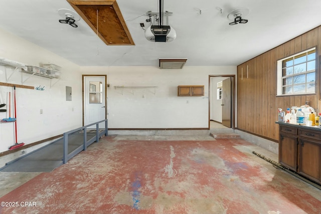 garage with baseboards, electric panel, a garage door opener, and wooden walls