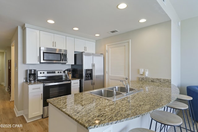 17739 Front Beach Rd Unit 1204W, Panama City Beach, FL 32413 - kitchen with stainless steel appliances, a kitchen bar, a peninsula, light wood-style flooring, and recessed lighting
