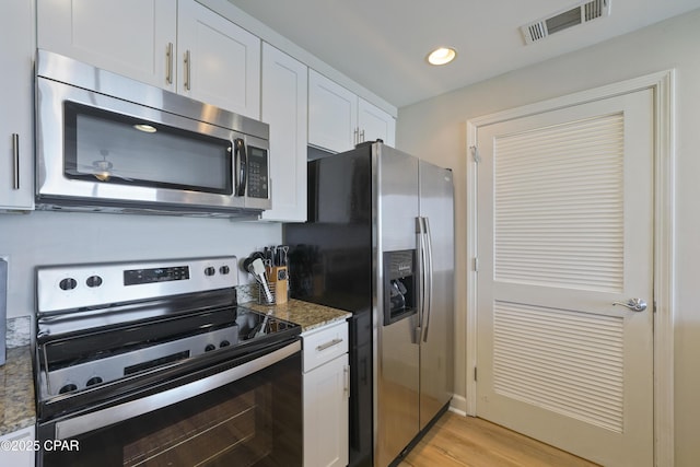 kitchen featuring stainless steel appliances, white cabinetry, dark stone counters, light wood finished floors, and recessed lighting