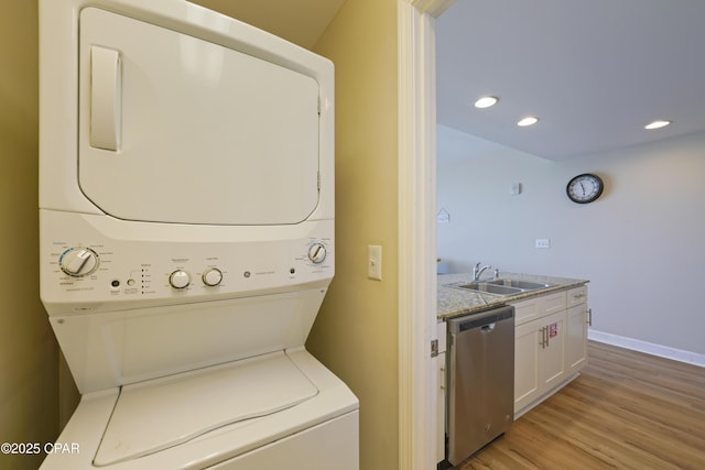 laundry area with stacked washer / dryer, light wood-type flooring, recessed lighting, and baseboards