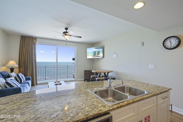 kitchen with a sink, white cabinetry, baseboards, a ceiling fan, and open floor plan