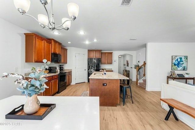 1527 Wateroak Dr, Lynn Haven, FL 32444 - kitchen featuring black appliances, arched walkways, light wood-style flooring, a breakfast bar, and recessed lighting