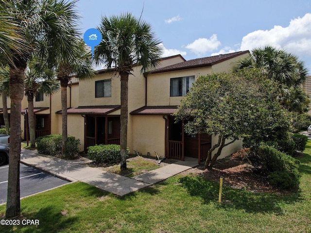 multi unit property featuring a front yard and stucco siding