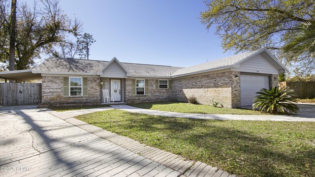 ranch-style house with fence, an attached garage, a shingled roof, a front yard, and brick siding