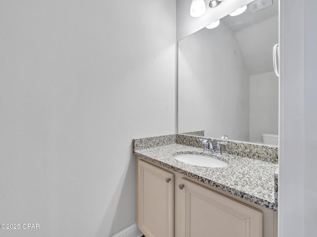 half bathroom featuring lofted ceiling and vanity
