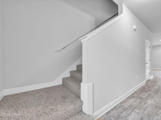 stairway with wood finished floors and baseboards