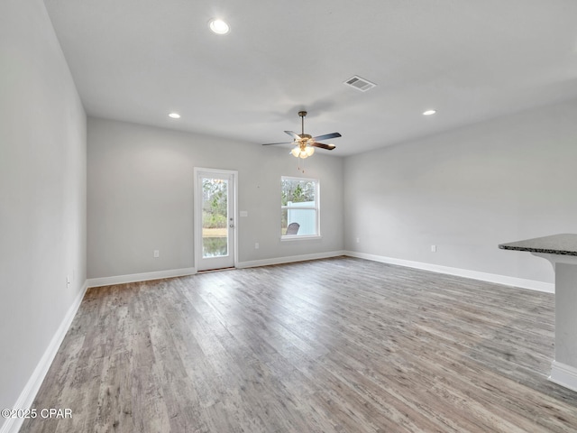 unfurnished living room with visible vents, baseboards, ceiling fan, and wood finished floors