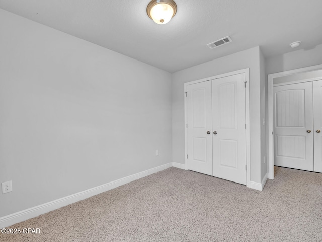 unfurnished bedroom with carpet flooring, baseboards, visible vents, and a closet