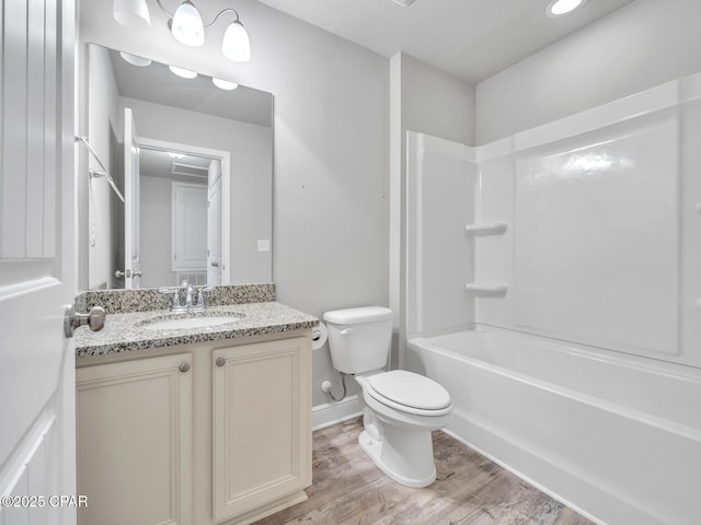 full bathroom with toilet, wood finished floors, baseboards, bathing tub / shower combination, and vanity