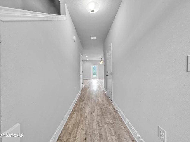 hallway featuring visible vents, wood finished floors, and baseboards