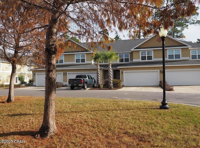 view of front of property featuring a front lawn, an attached garage, driveway, and stucco siding