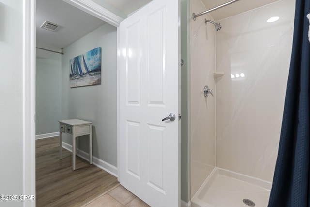 9900 S Thomas Dr Unit 425, Panama City, FL 32408 - full bathroom featuring wood finished floors, a shower stall, baseboards, and visible vents