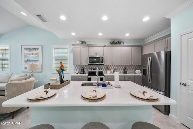 kitchen with visible vents, a kitchen bar, gray cabinets, a sink, and stainless steel appliances