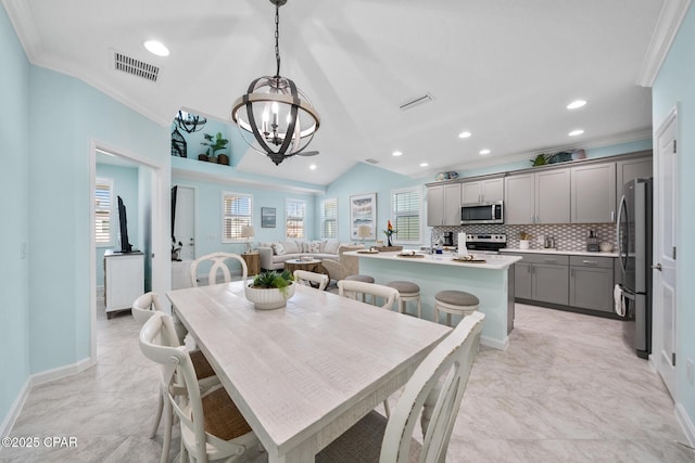 dining area featuring visible vents, ornamental molding, vaulted ceiling, and an inviting chandelier