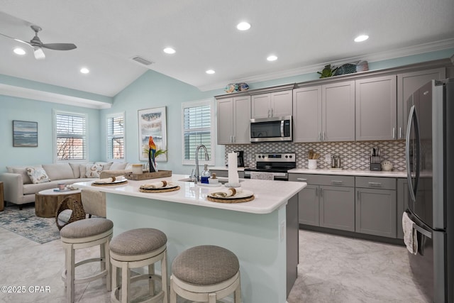kitchen featuring visible vents, lofted ceiling, gray cabinets, a sink, and appliances with stainless steel finishes