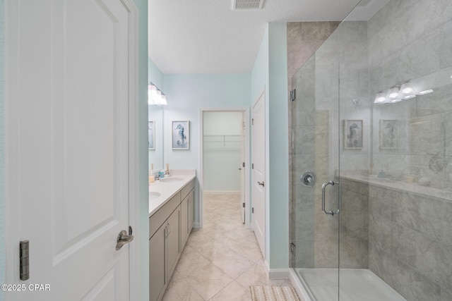 full bath featuring a walk in closet, a sink, double vanity, baseboards, and a shower stall