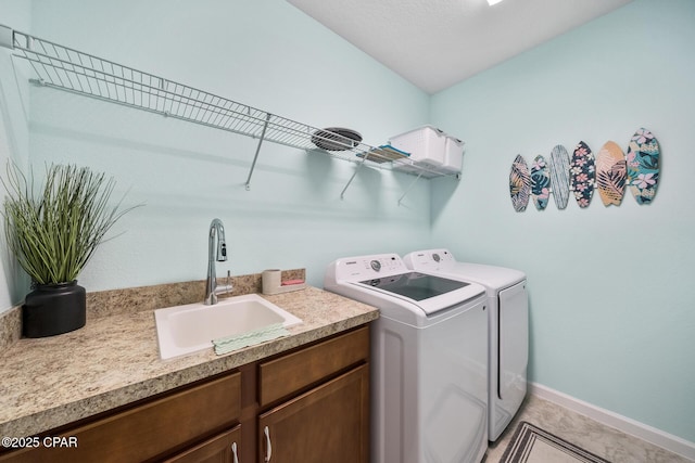 clothes washing area featuring a sink, baseboards, light tile patterned floors, and washer and dryer