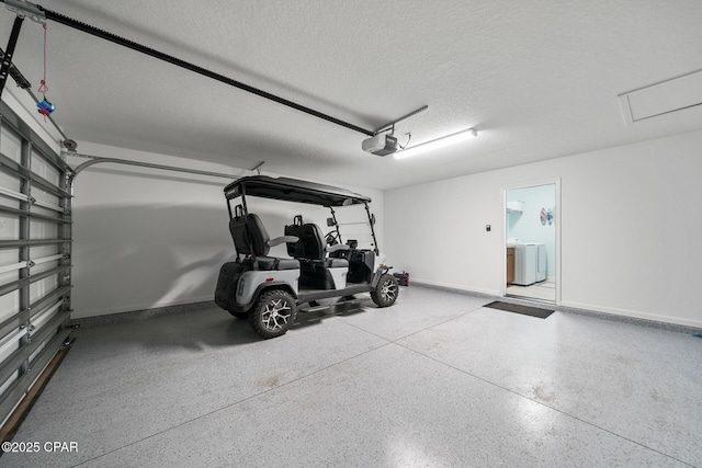 garage featuring baseboards, a garage door opener, and washer / clothes dryer