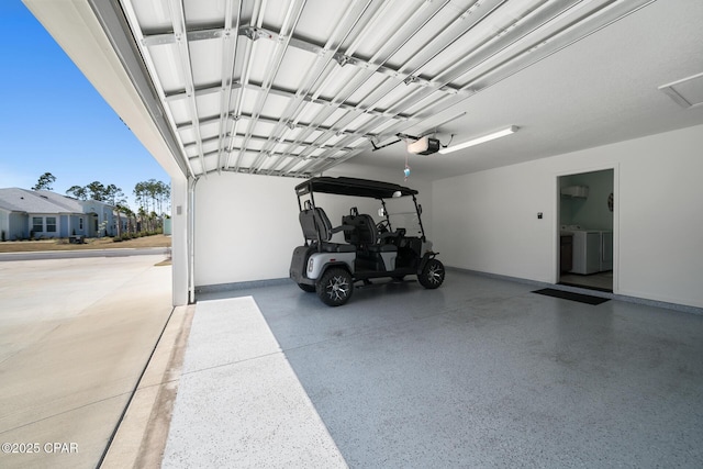 garage with independent washer and dryer, baseboards, and a garage door opener