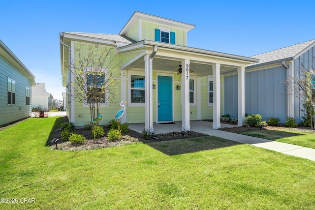 bungalow with a porch, ceiling fan, board and batten siding, and a front yard