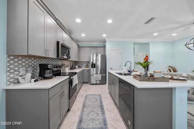 kitchen with gray cabinets, crown molding, a sink, stainless steel appliances, and an island with sink
