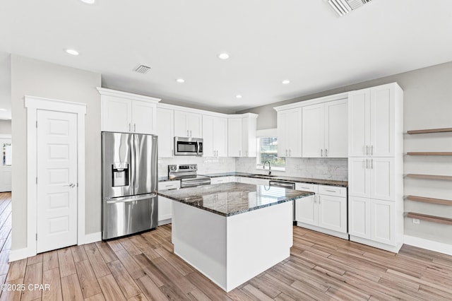 kitchen featuring a sink, a center island, stainless steel appliances, visible vents, and white cabinets